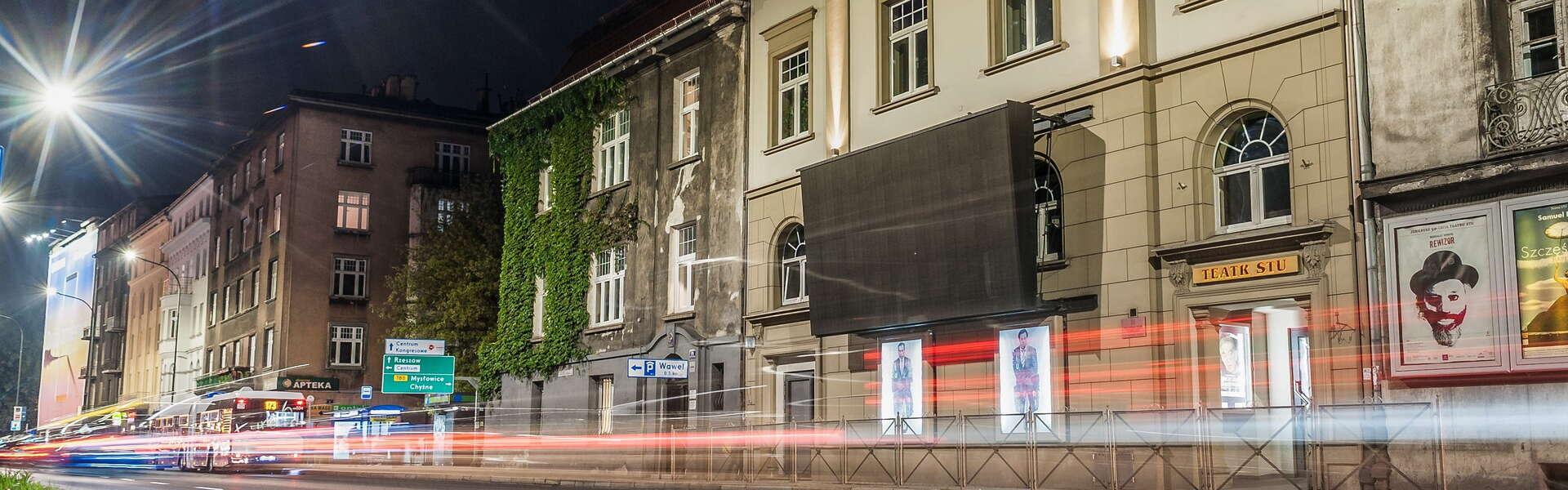 Budynek Teatru Stu w ciągu budynków przy krakowskiej alei Zygmunta Krasińskiego widziany nocą