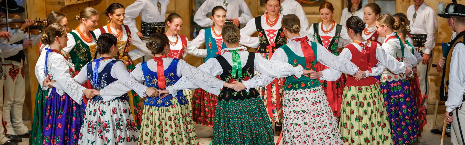 Góralki w ludowych strojach, tańczące wspólnie na scenie