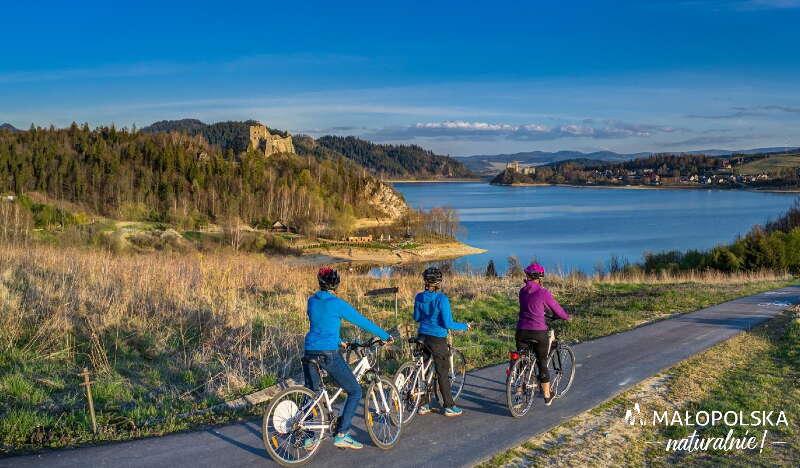 Three people on bikes admiring the view of the lake and the castle.