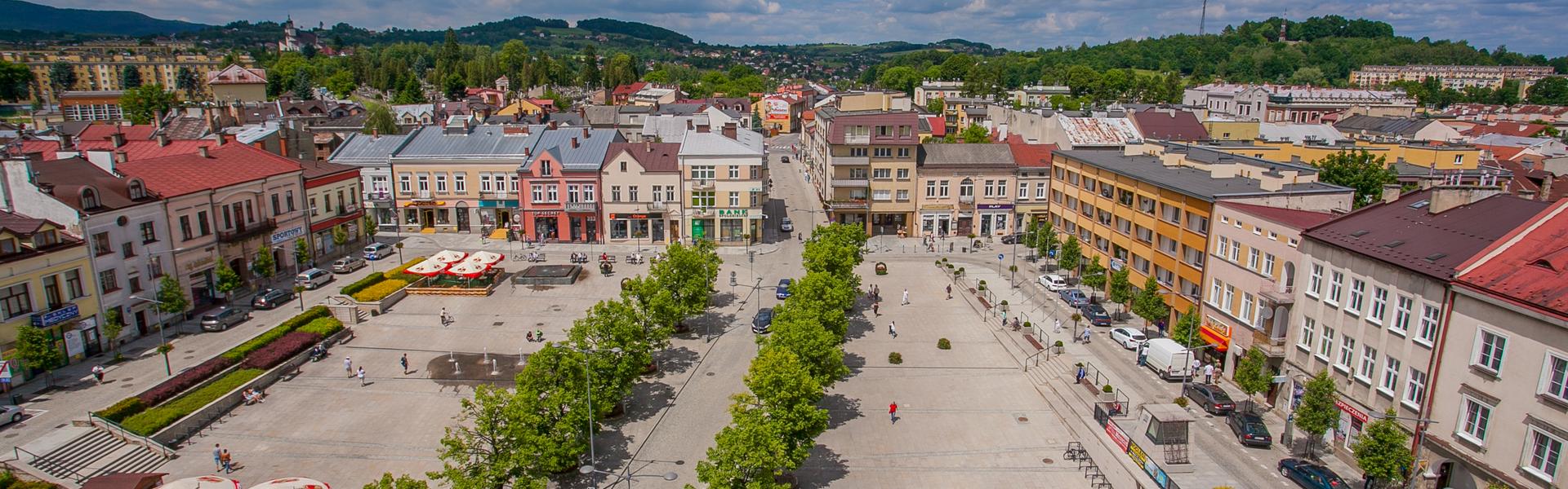 Marktplatz von Gorlice, Blick auf Stadthäuser, Platz und Baumalleen aus der Vogelperspektive.