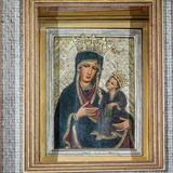 Obraz Matki Bożej z Dzieciątkiem, w ciemnych sukienkach, z koronami na głowach, w złotej ramie.