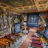 Wnętrze drewnianego kościoła. Ołtarze zasłonięte ciemnymi płótnami z malowidłami. Po lewej stronie bogato zdobiony prospekt organowy. Na suficie i ścianach bogata polichromia.