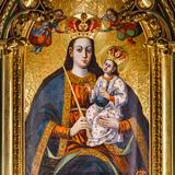 Obraz Matki Boskiej z Dzieciątkiem w złotej ramie, ze złotymi koronami na głowie Matki Boskiej i Dzieciątka. Matka Boska trzyma małego Jezusa na kolanach.