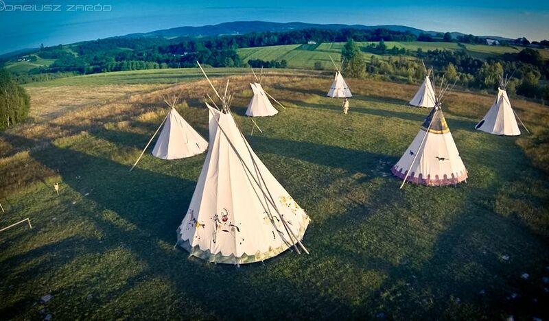 7 indiańskich namiotów ustawionych na łące w zielonym krajobrazie Pogórzy. Zdjęcie z drona.
