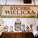namalowany napis Kuchnia Wielicka wraz z solniczkami, obok stojące manekiny