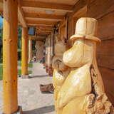 Drewniana rzeźba Muminka Włóczykija stojąca w podcieniu budynku Chatka Włóczykija