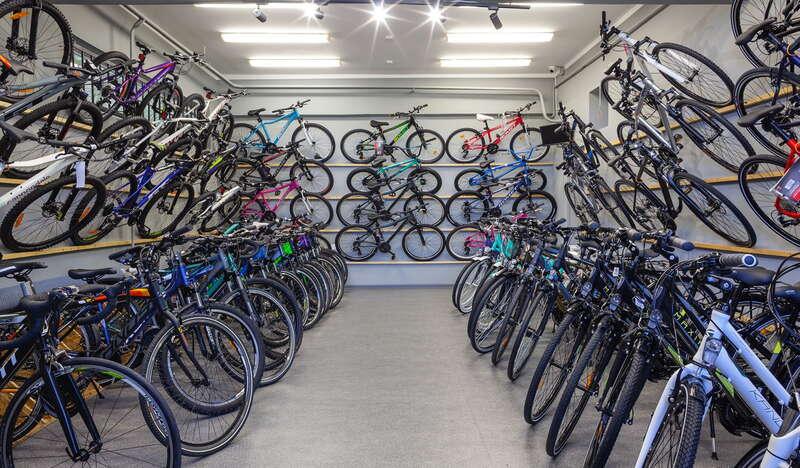 Kilkadziesiąt rowerów zawieszonych na specjalnych półkach, od podłogi aż po sufit.
