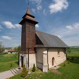 Kościół murowany, niewielki z kamienno-drewniana wieżą, wokół ładnie uporządkowany teren zielony.